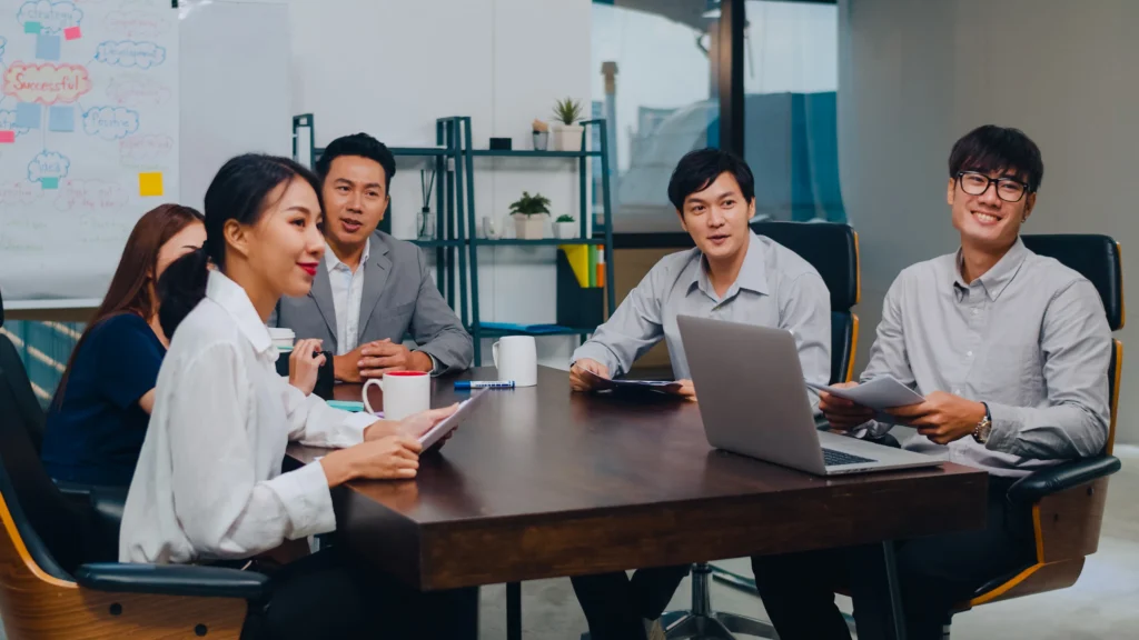 A diverse group of professionals in a modern office setting, engaged in a friendly conversation or a small meeting. 